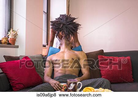 Stock Photo - Couple kissing on sofa in living room. Fotosearch