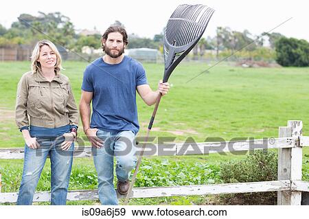 Stock Photo - Couple leaning on wooden fence. Fotosearch