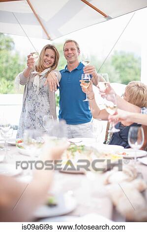 Couple making toast at table View Large Photo Image Stock Photograph - Couple making toast at table. Fotosearch