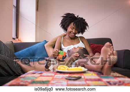 Couple relaxing on sofa in living room View Large Photo Image Stock Image - Couple relaxing on sofa in living room. Fotosearch