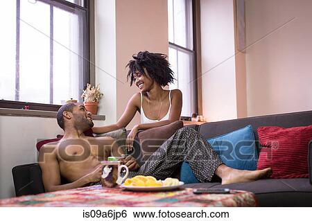 Stock Photograph - Couple relaxing on sofa in living room. Fotosearch