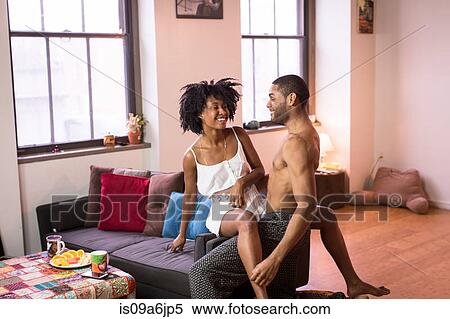 Couple sitting on sofa in living room View Large Photo Image Stock Photography - Couple sitting on sofa in living room. Fotosearch