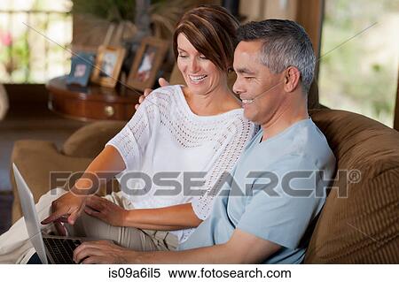 Couple using laptop together on sofa View Large Photo Image Stock Photography - Couple using laptop together on sofa. Fotosearch