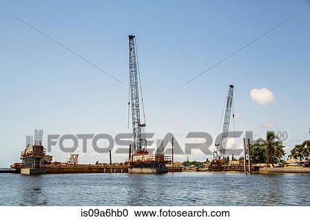 Stock Image - Cranes at construction site on water. Fotosearch