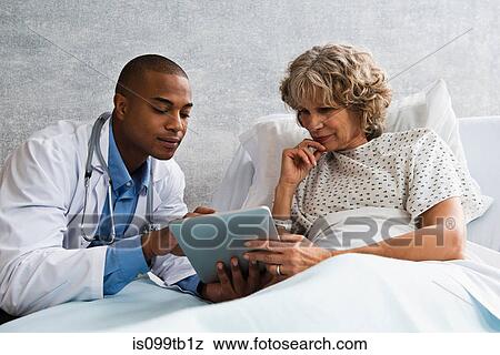 Doctor showing digital tablet to patient in hospital View Large Photo Image Stock Photo - Doctor showing digital tablet to patient in hospital. Fotosearch