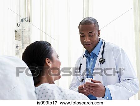 Doctor talking to patient in hospital, looking at medicine View Large Photo Image Stock Photo - Doctor talking to patient in hospital, looking at medicine. Fotosearch