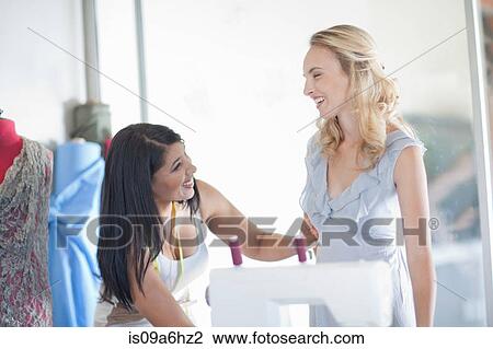 Stock Image - Dressmaker fitting client in studio. Fotosearch