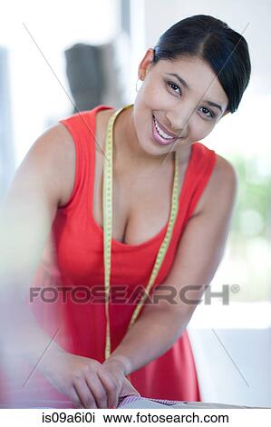 Stock Image - Dressmaker smiling in studio. Fotosearch
