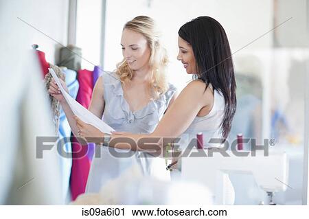 Stock Image - Dressmaker working with client in studio. Fotosearch