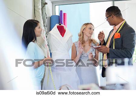Stock Image - Dressmakers working with client. Fotosearch