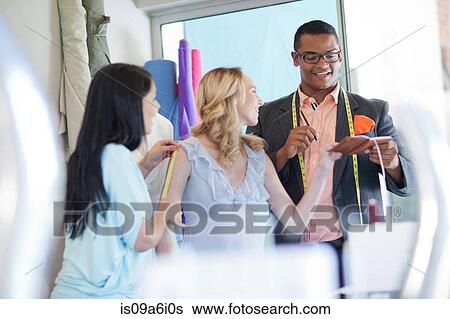 Stock Photograph - Dressmakers working with client. Fotosearch