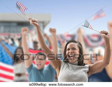 Stock Image - Excited woman waving american flags at rally. Fotosearch