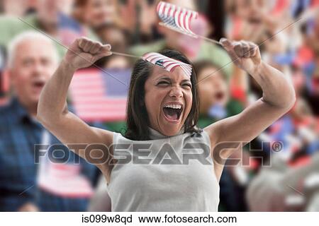 Stock Image - Excited woman waving american flags at rally. Fotosearch