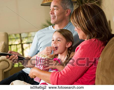 Stock Image - Family relaxing together on sofa. Fotosearch