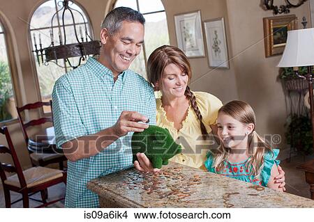 Picture - Family saving money in green piggy bank. Fotosearch