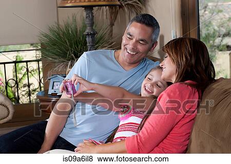 Stock Photo - Family taking pictures together on sofa. Fotosearch