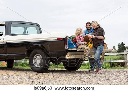 Stock Image - Family with produce in truck bed. Fotosearch