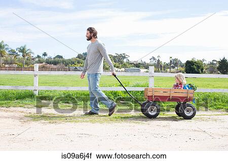 Stock Image - Father pulling son in wagon. Fotosearch