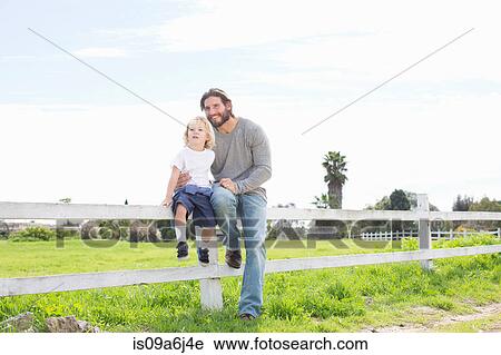 Stock Image - Father with son on wooden fence. Fotosearch