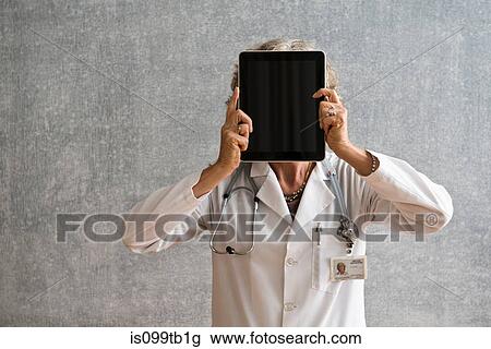 Stock Image - Female doctor holding digital tablet in front of face. Fotosearch