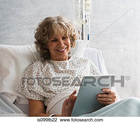 Stock Image - Female hospital patient using digital tablet. Fotosearch