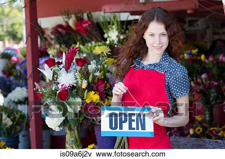 Stock Photo - Florist hanging open sign in shop. Fotosearch
