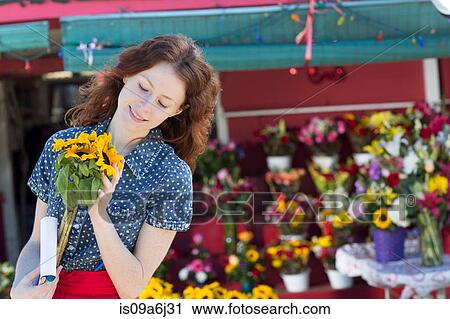 Stock Image - Florist holding flowers in shop. Fotosearch