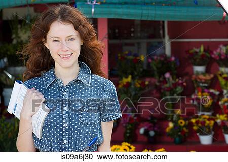 Stock Image - Florist holding notepad in shop. Fotosearch