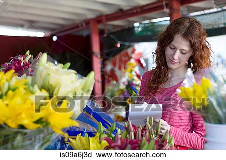 Stock Image - Florist making notes in shop. Fotosearch