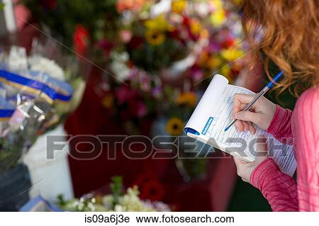 Stock Image - Florist making notes in shop. Fotosearch