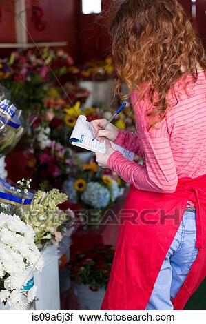 Stock Image - Florist making notes in shop. Fotosearch