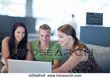 Friends using laptop on sofa View Large Photo Image Stock Photo - Friends using laptop on sofa. Fotosearch