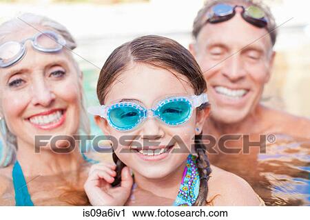 Stock Image - Girl and grandparents swimming in pool. Fotosearch