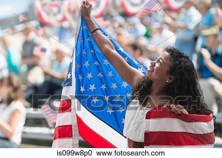 Stock Image - Girl at rally holding up american flag. Fotosearch