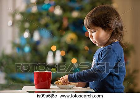 Stock Image - Girl eating Christmas cookies. Fotosearch