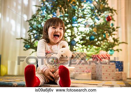 Stock Photo - Girl laughing by Christmas tree. Fotosearch