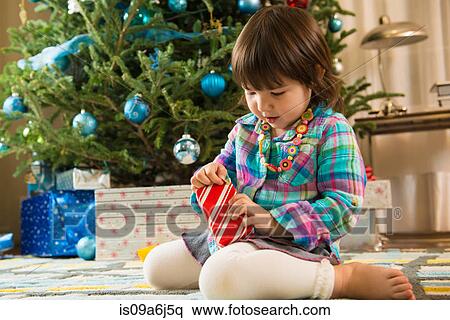 Stock Photography - Girl opening Christmas gift. Fotosearch