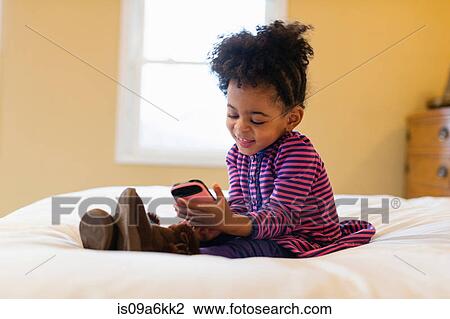 Girl playing with cell phone on bed View Large Photo Image Stock Image - Girl playing with cell phone on bed. Fotosearch