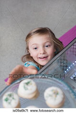 Girl reaching for cupcakes in bakery View Large Photo Image Stock Photograph - Girl reaching for cupcakes in bakery. Fotosearch