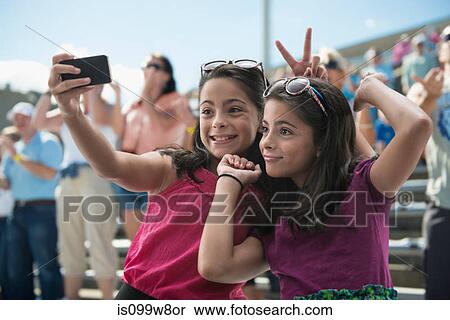 Stock Photography - Girls taking a picture of themselves at pop concert. Fotosearch