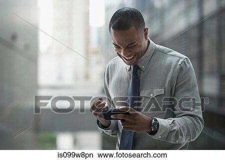 Picture - Happy businessman looking at smartphone. Fotosearch