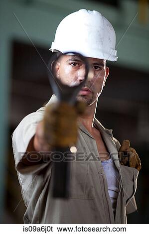 Industrial worker holding tool in plant View Large Photo Image Stock Photograph - Industrial worker holding tool in plant. Fotosearch