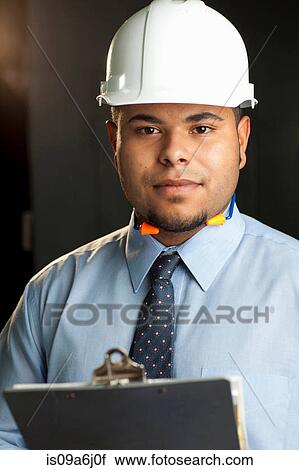 Stock Image - Industrial worker reading clipboard. Fotosearch