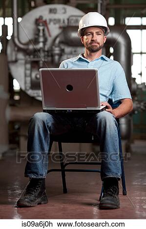 Stock Image - Industrial worker using laptop. Fotosearch