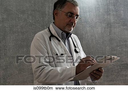 Picture - Male doctor writing on chart. Fotosearch