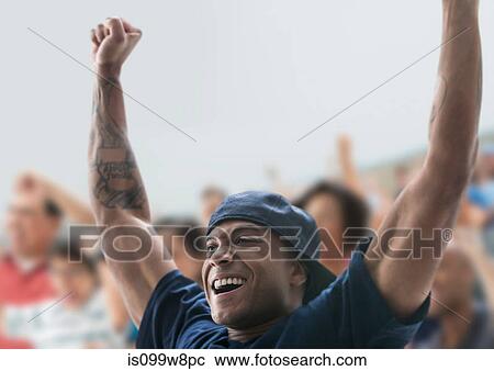 Stock Image - Man at sports game with arms raised. Fotosearch