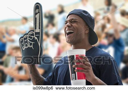Man at sports game with foam hand and soft drink cup View Large Photo Image Stock Photograph - Man at sports game with foam hand and soft drink cup. Fotosearch
