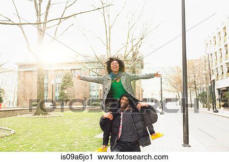 Stock Image - Man carrying girlfriend on shoulders. Fotosearch
