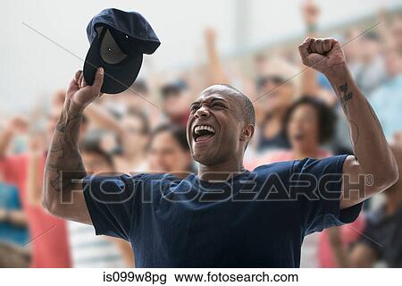 Man cheering at sports game, holding baseball cap View Large Photo Image Stock Image - Man cheering at sports game, holding baseball cap. Fotosearch
