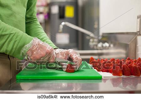 Stock Photograph - Man chopping strawberries in kitchen. Fotosearch